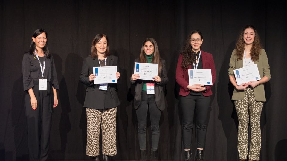 A man and a woman stand by the podium in discussion. Behind them on the screen you can see the Karolinska University Hospital and the Karolinska Institutet.