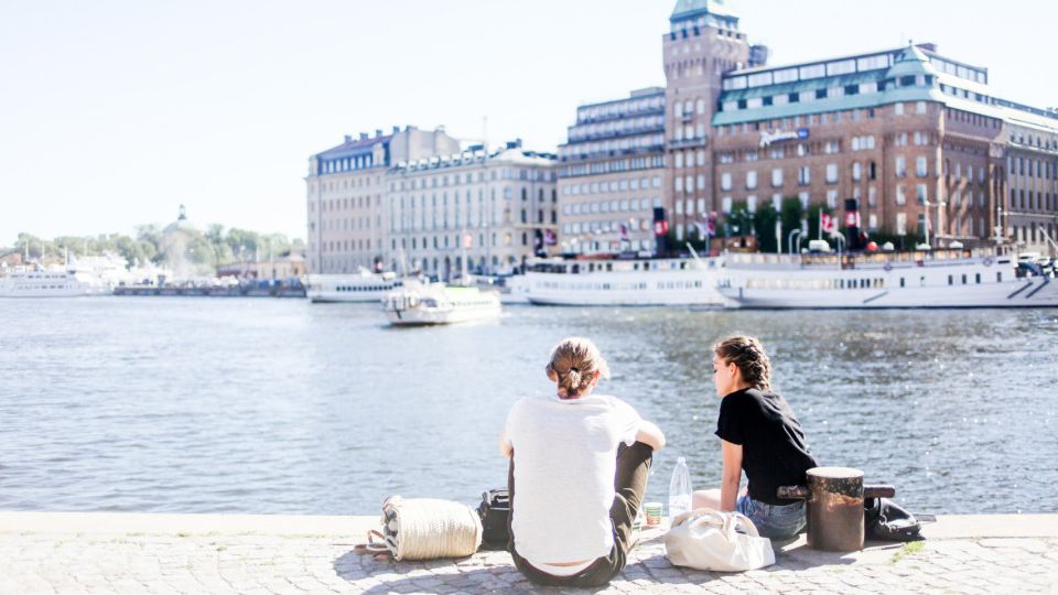 Two people sitting on the bank of a river.