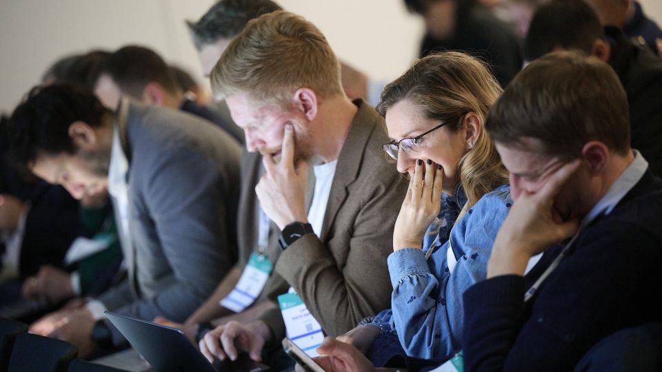 A man and a woman stand by the podium in discussion. Behind them on the screen you can see the Karolinska University Hospital and the Karolinska Institutet.