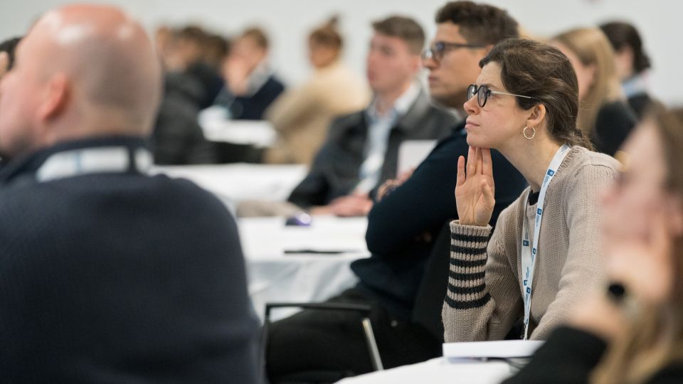 A man and a woman stand by the podium in discussion. Behind them on the screen you can see the Karolinska University Hospital and the Karolinska Institutet.