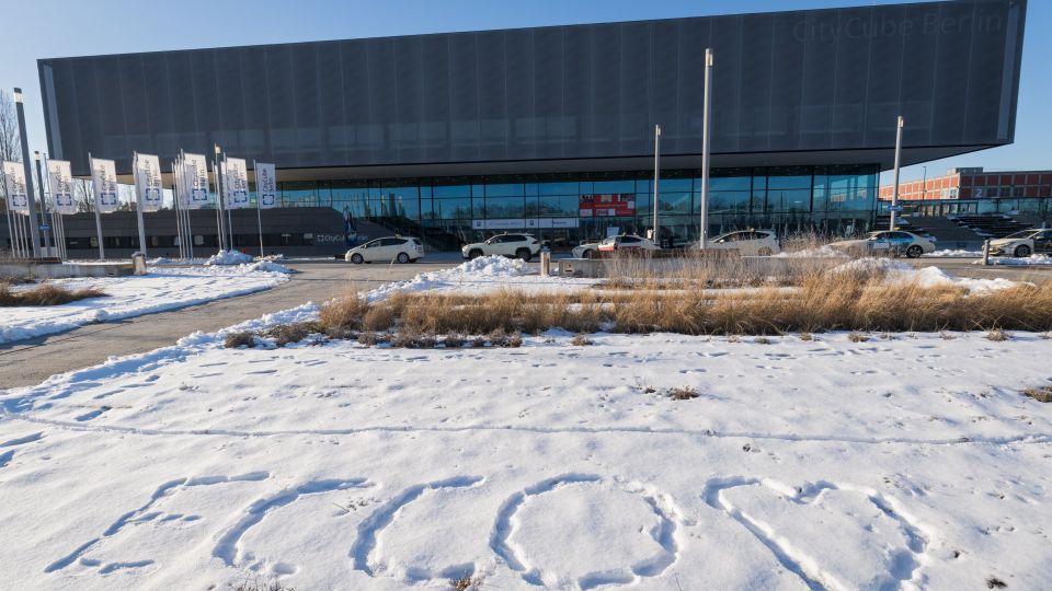 A man and a woman stand by the podium in discussion. Behind them on the screen you can see the Karolinska University Hospital and the Karolinska Institutet.