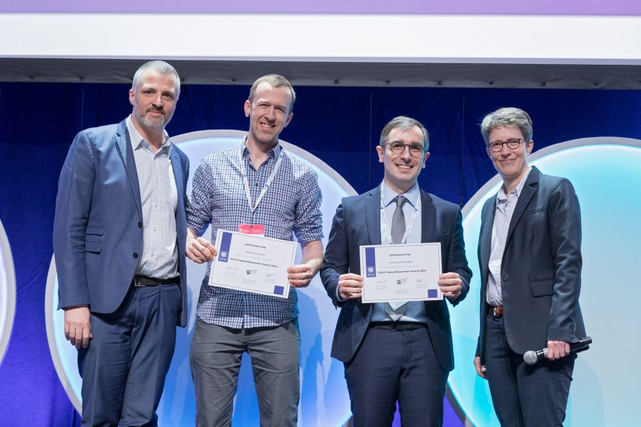 Both, Jakob Zimmerman and Jo&atilde;o Sabino, holding an Award Cerificate are joined by Marc Ferrante and Britta Siegmund on stage.