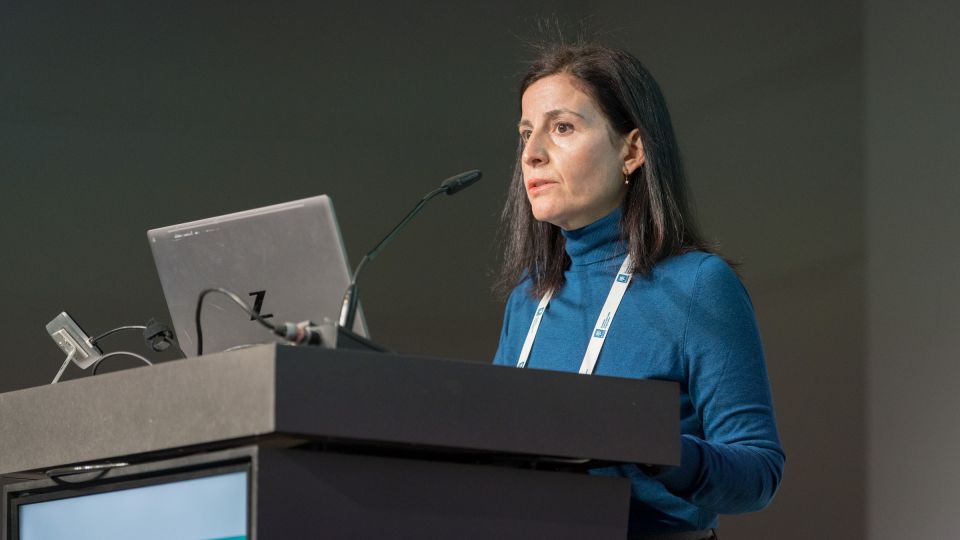 A man and a woman stand by the podium in discussion. Behind them on the screen you can see the Karolinska University Hospital and the Karolinska Institutet.