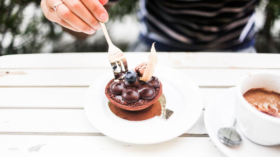 A hand adorned with a ring holds a fork piercing a delicious looking chocolate dessert.