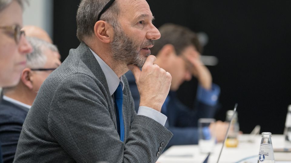 A member of the operational board rests their chin on their hand and speaks to the operational board.