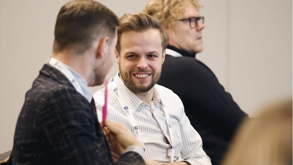 Marc Ferrante and Konstantinos Papamichail sit next to the podium behind a long desk. In the background you can see the speakers conversing and the screen with a graphic of the Swedish Inflamatory Bowel Disease Registry.