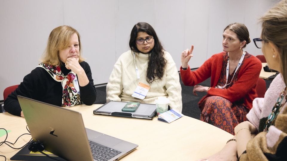 A man and a woman stand by the podium in discussion. Behind them on the screen you can see the Karolinska University Hospital and the Karolinska Institutet.